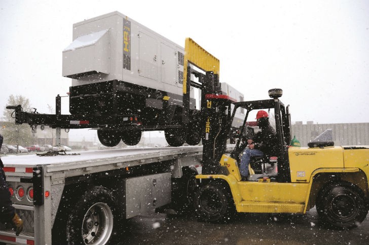 A generator equipped with a snow hood being loaded for delivery.