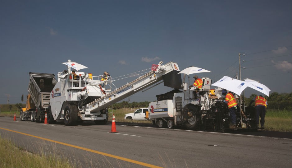 A truck supplies asphalt to the material transfer vehicle (MTV), which loads the paver.