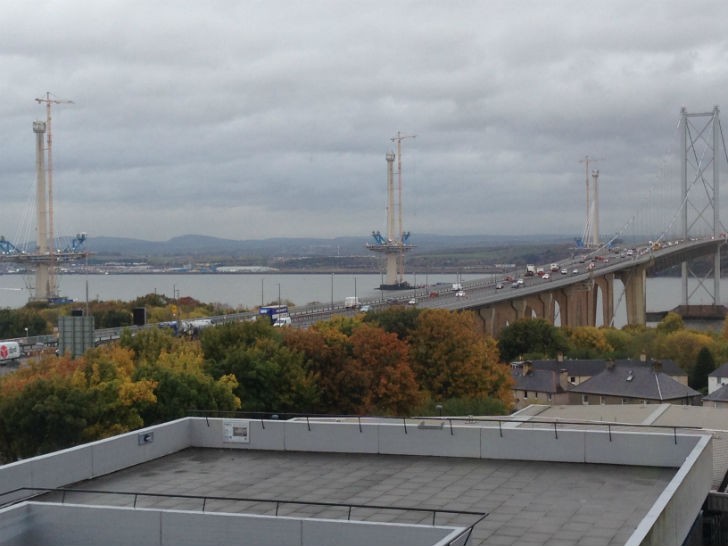 View of the three concrete towers with Liebherr tower cranes alongside them, taken from the Queensferry Crossing Contact and Education Centre.