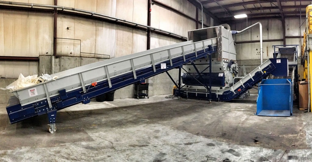 Tailor-made for Winco Plastics: Lindner's re-grinding line includes a conveyor belt (left) to feed the Micromat 2500 Pre-Shredder, followed by two successive conveying belts with a metal detector, used to feed a Lindner LG 1500-800 grinder (on the right behind the Gaylord dumper). 