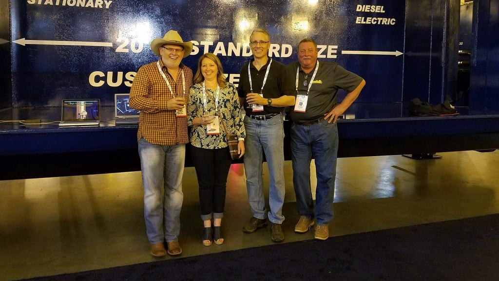The owners of OverBuilt, at ISRI in April, in front of a 2018 Model 10 HS Car Crusher. From left to right: Gary Reichling, Kellee Pace and Don Roby, along with sales manager Steve Besch.