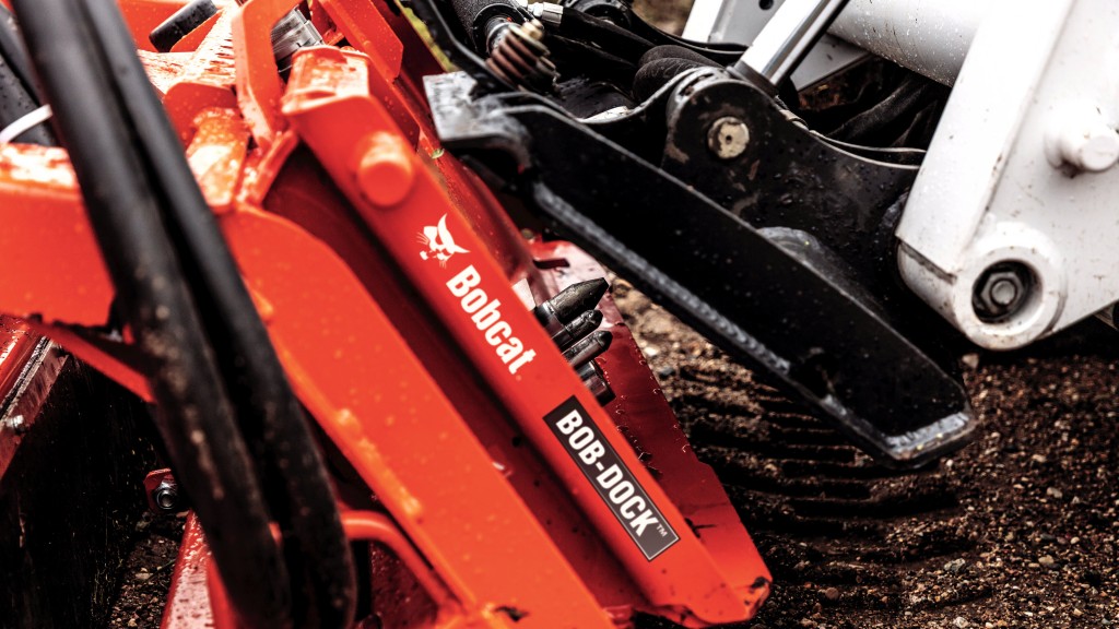 To connect an attachment to a compact loader equipped with the Bob-Dock system, an operator lines up the loader with the attachment's Bob-Dock adapter plate.