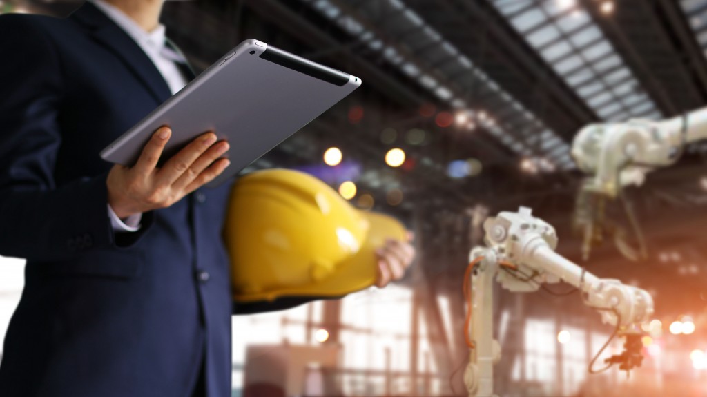 Man holding a tablet with a construction hat in hand