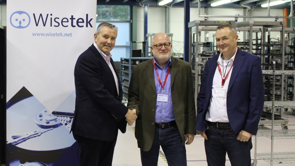 three men shake hands in front of Wisetek logo