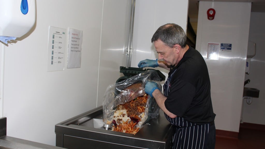 man depositing food waste into composter