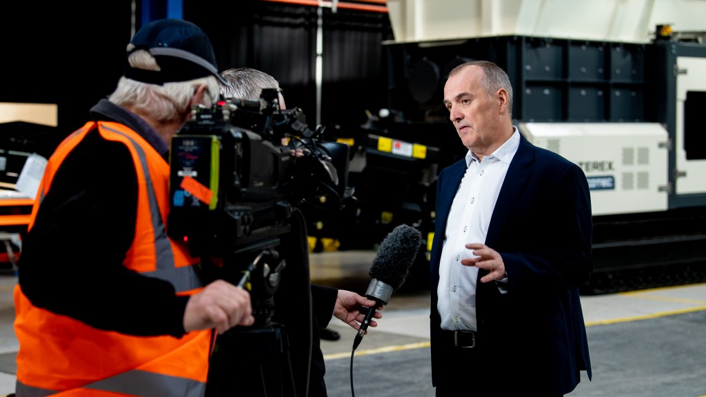 man being interviewed near terex machine