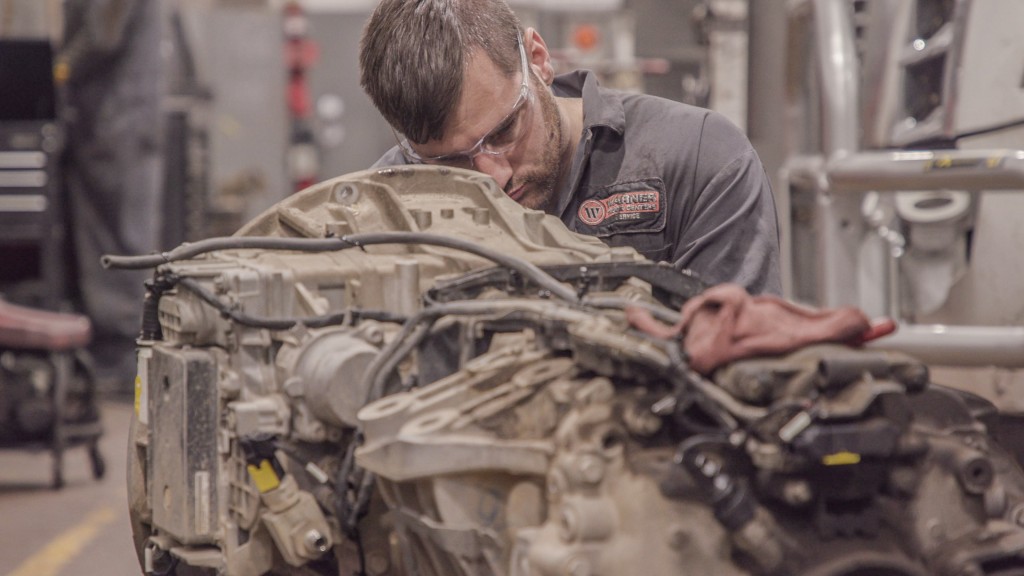 A daimler mechanic works on a truck part