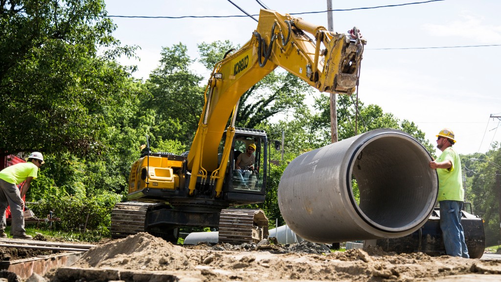 An excavator lifting a concrete sewer pipe