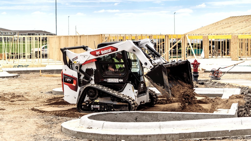 Bobcat compact track loader dumps dirt on building site