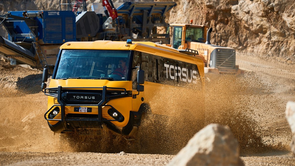 A Torsus Praetorian off-road bus splashing through a puddle in a quarry