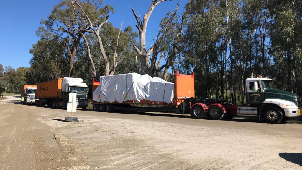 a line of tractor trailers carrying goods down a road