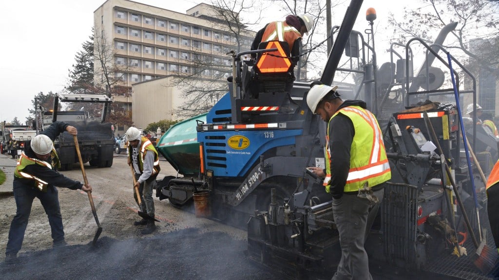 Paving crew working around asphalt paver