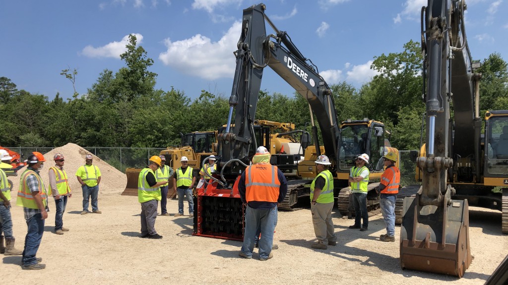 workers hanging around a John Deere machine at a worksite