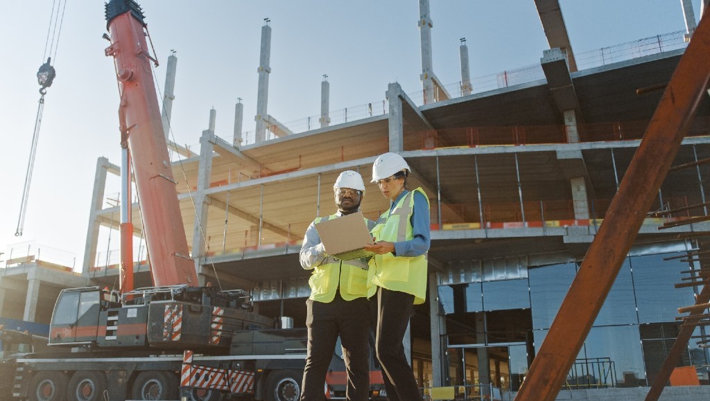 Workers in front of a crane and construction site