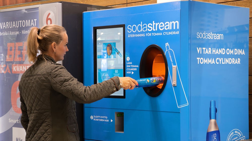 woman puts Sodastream bottle into Tomra reverse vending machine