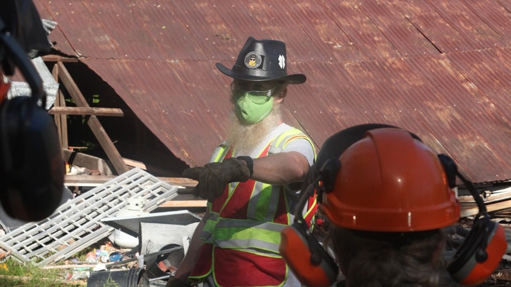 worker with a mask on gives direction on a disaster worksite