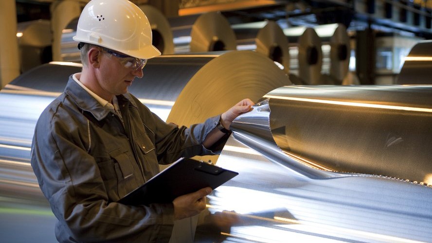 man tears piece of tin foil at aluminum plant