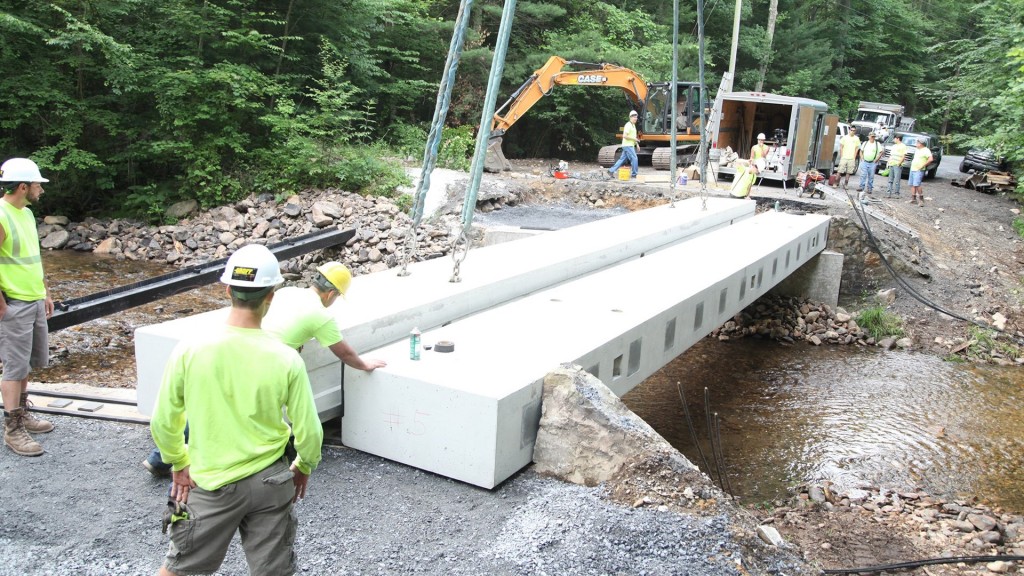 men work on building a bridge across a narrow river