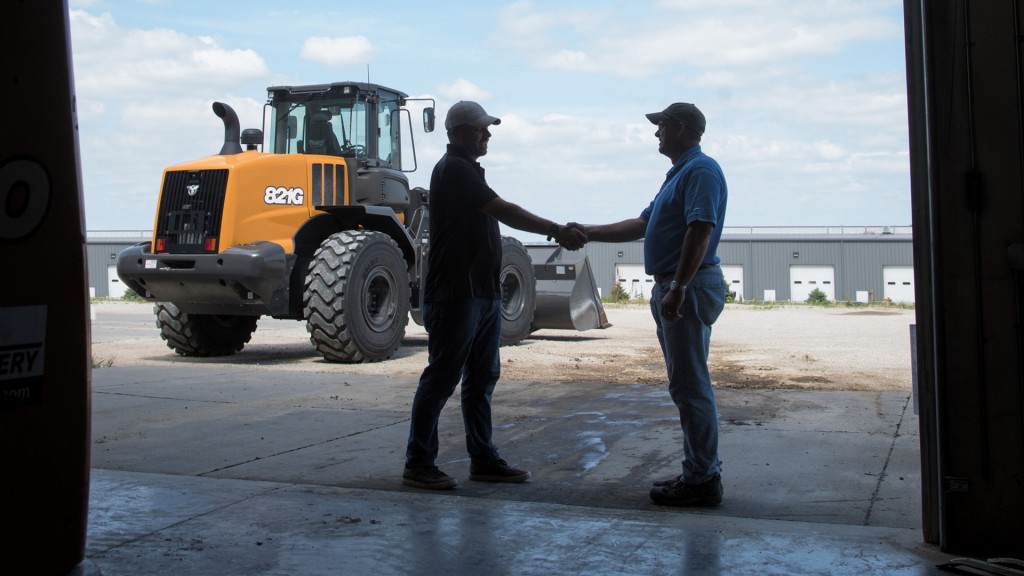 two men shake hands in front of case machine