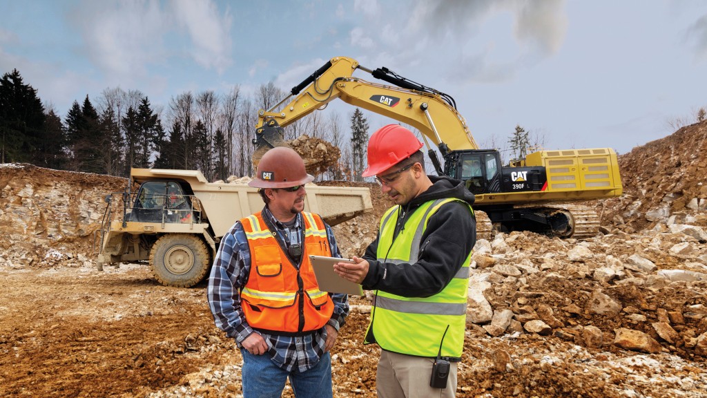 Construction workers on a job site look at a tablet