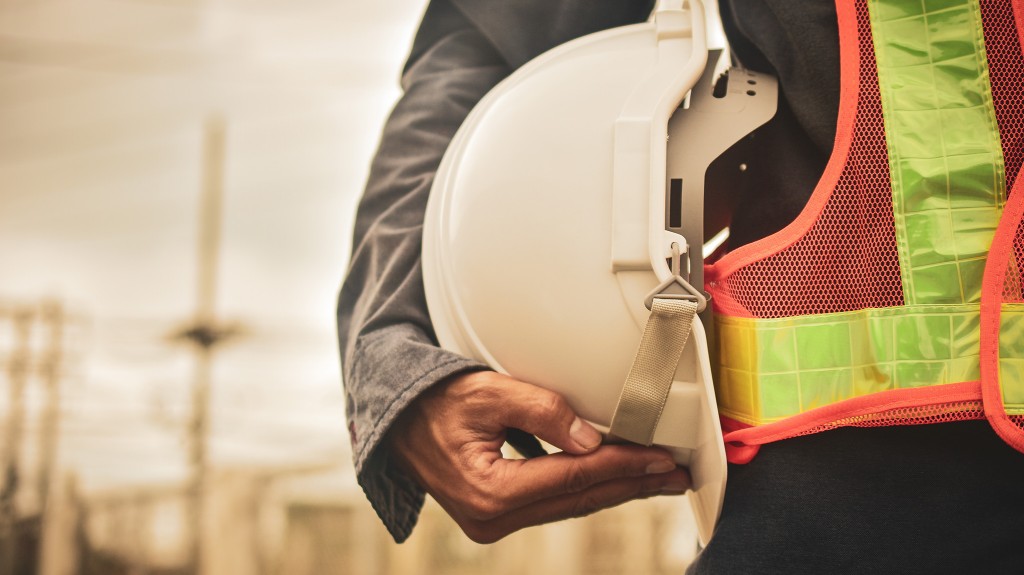 A construction worker holds their helmet