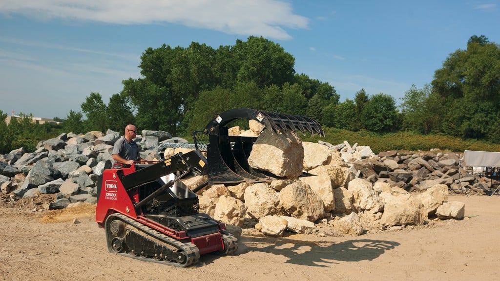 Toro compact utility loader moves large rock with grapple attachment