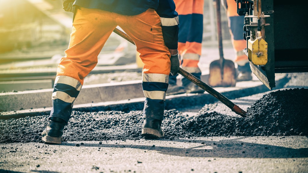 worker shovels asphalt on a paving job