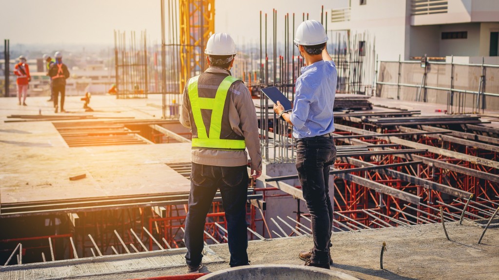 Two workers interact with a tablet on a job site