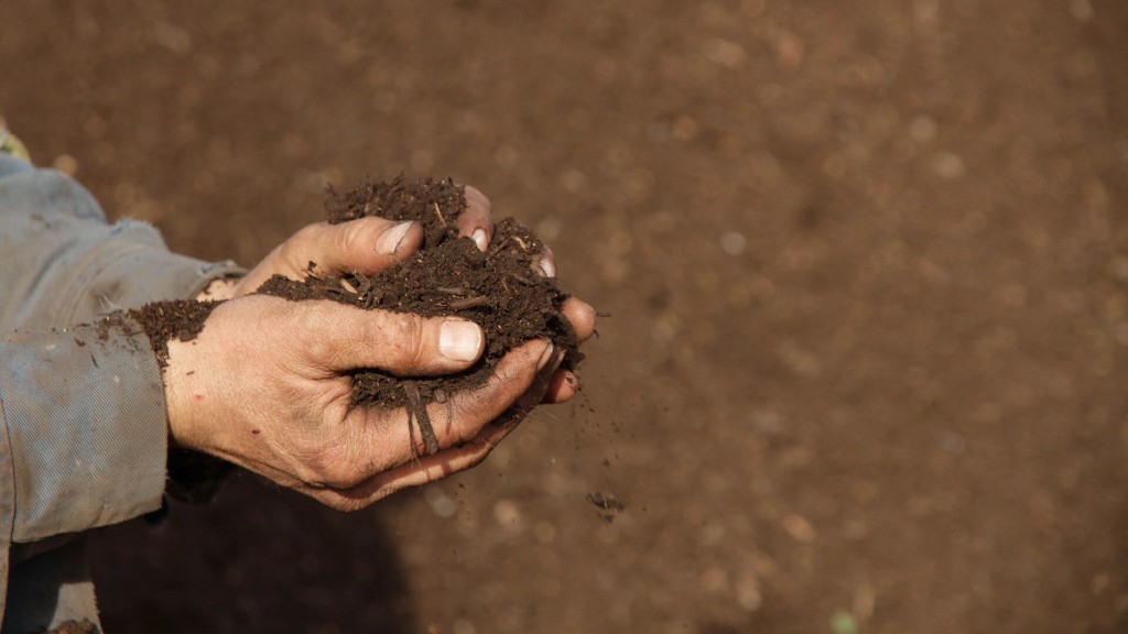 A farmer holds a pile of compost dirt