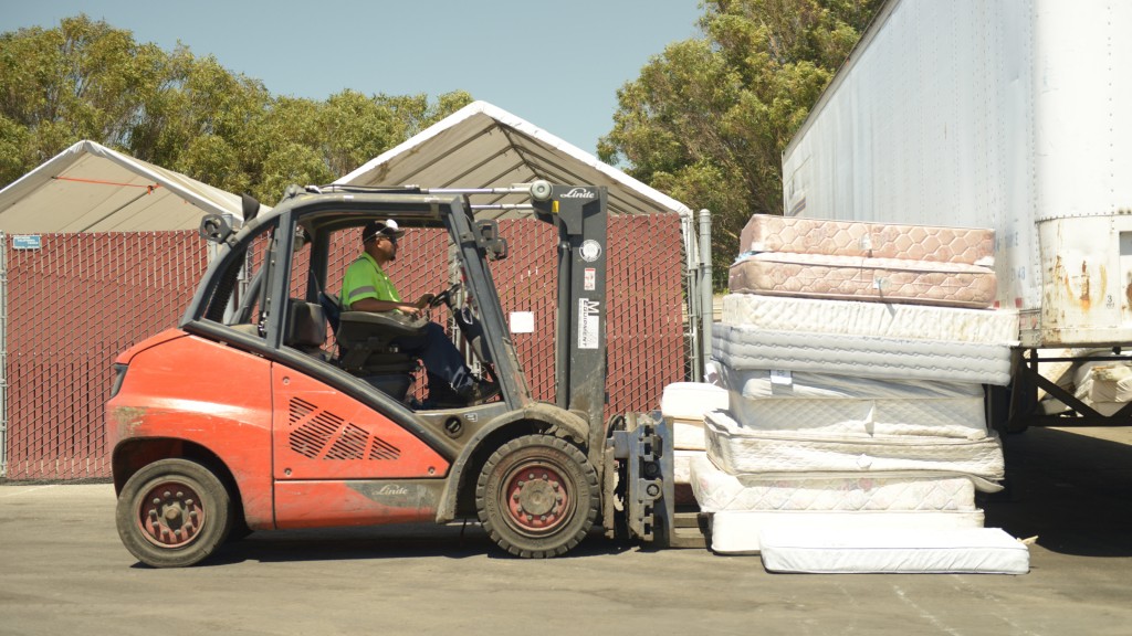 A forklift moves a pile of mattresses.