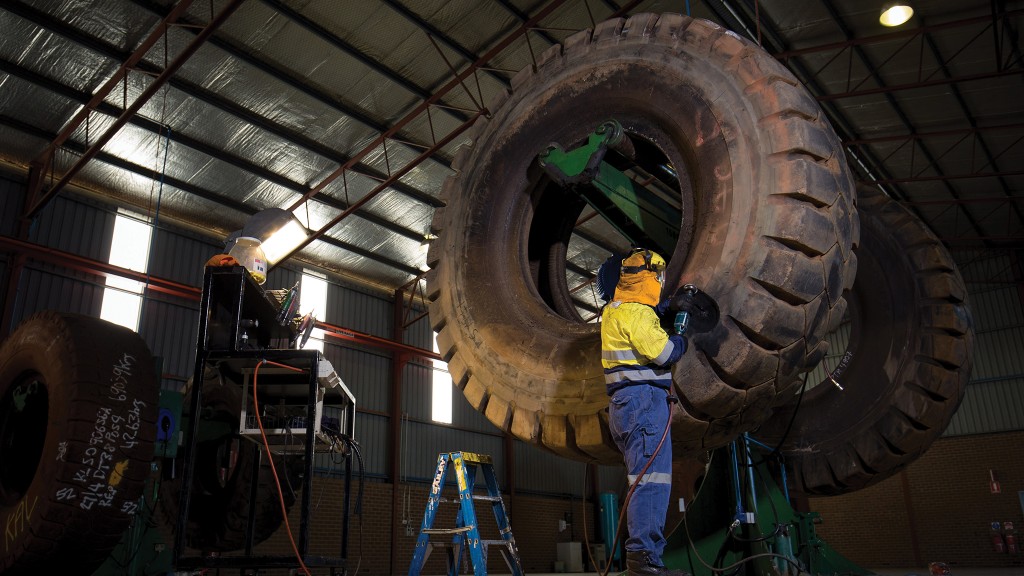 Two workers repair a large tire