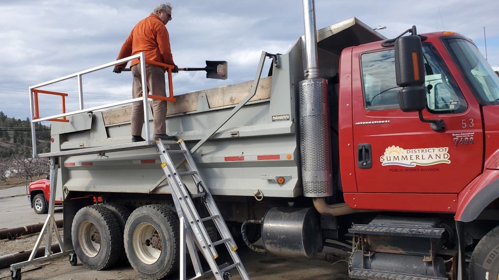 Worker on Sturdy Deck work platform next to a dump truck