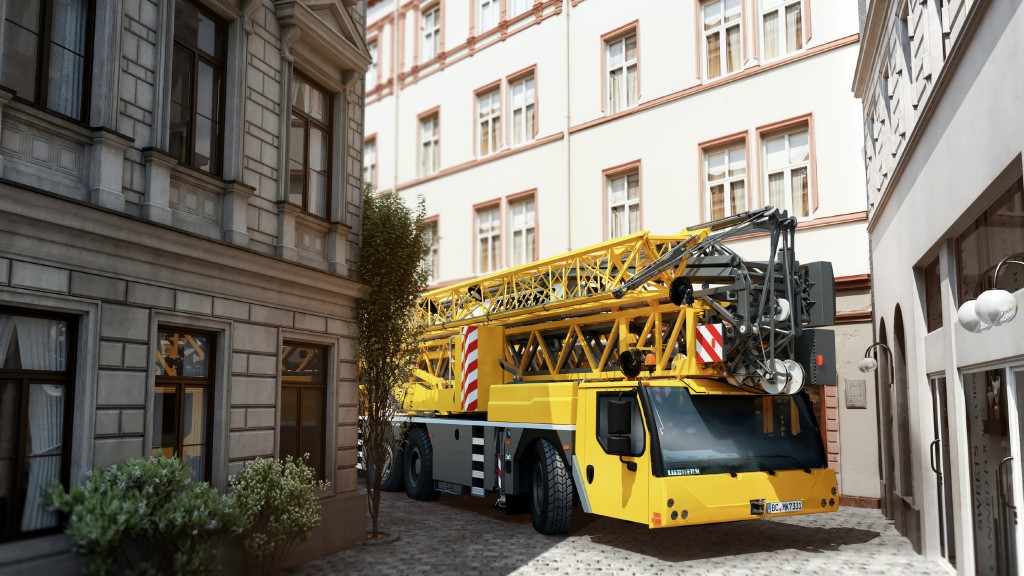 A yellow Liebherr all-terrain crane turning a corner between buildings