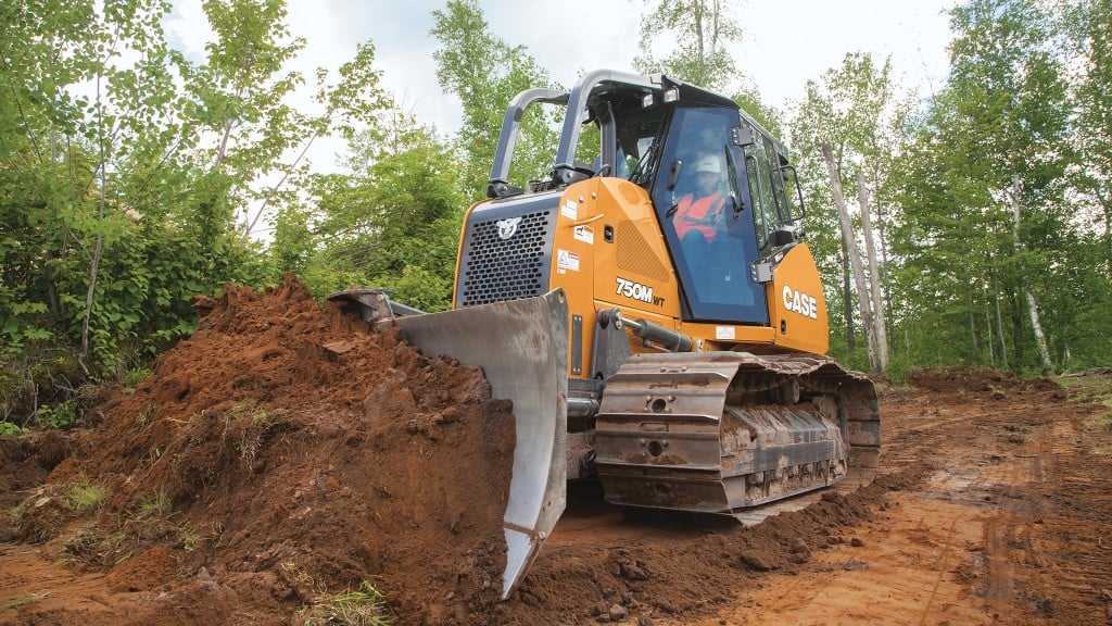 CASE dozer pushes dirt in forest clearing