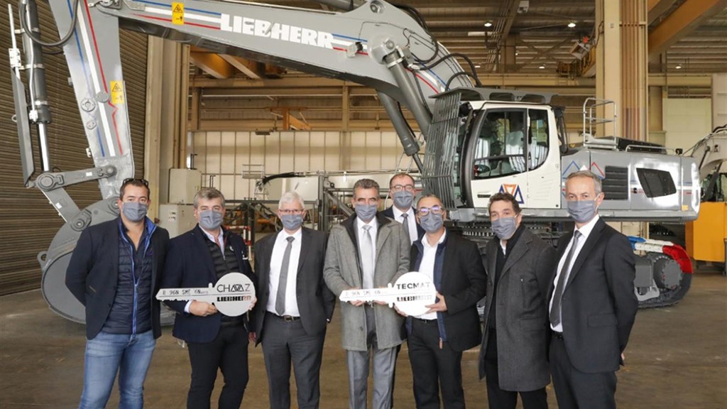 Liebherr executives stand in front of an excavator
