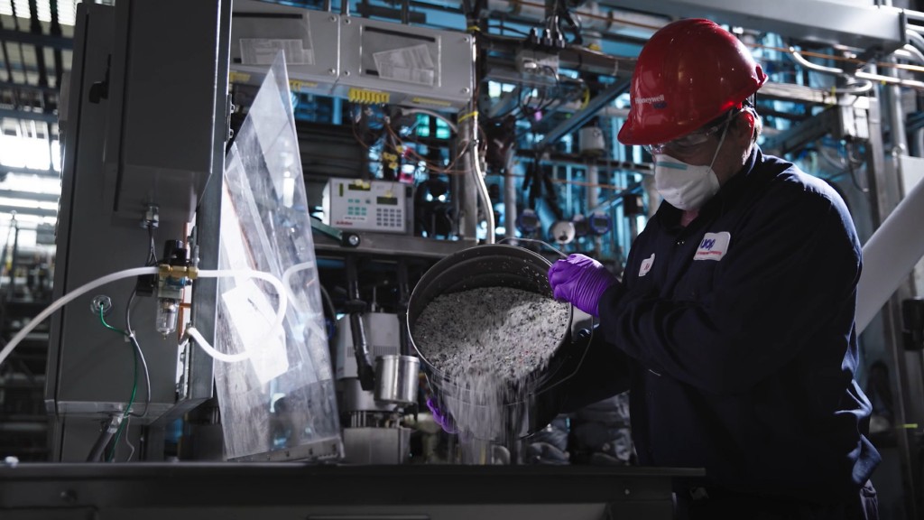 A worker pours plastic pellets out of a bucket and into a machine