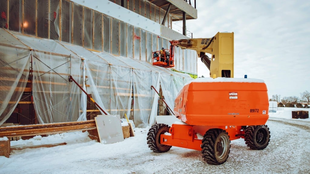 A JLG boom lift operates on a snowy job site