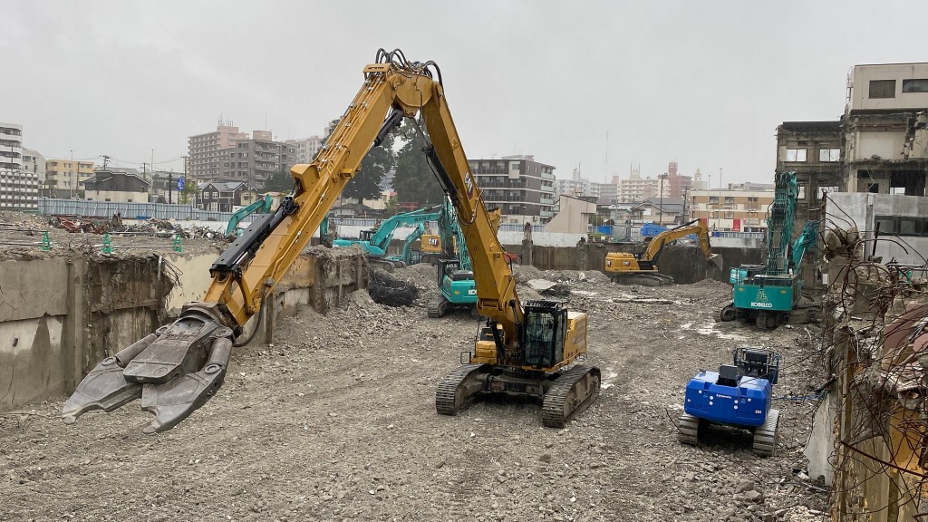 A demolition excavator with shear attachment outstretched in front of it