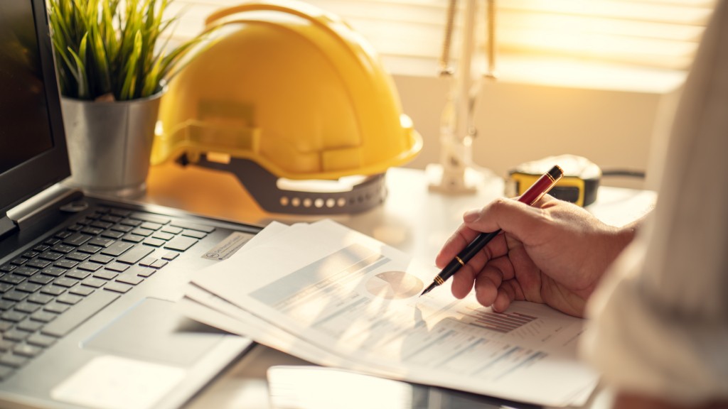 A construction worker reads paperwork on their desk