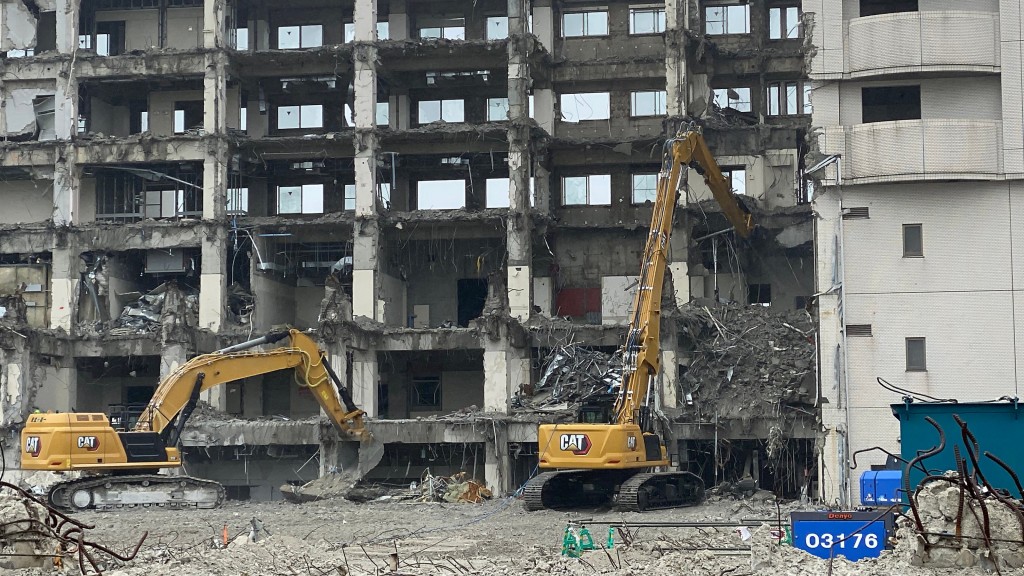 A Cat demolition excavator demolishes a building