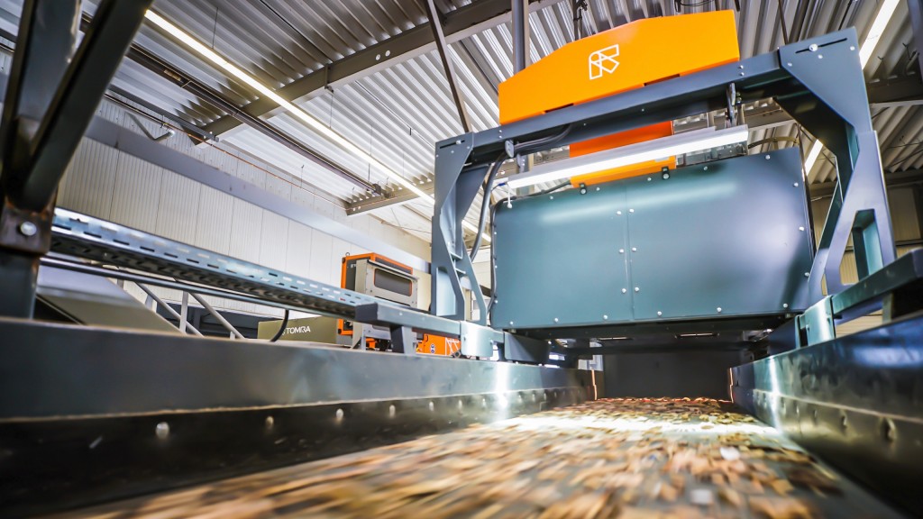 A conveyor moves wood debris into a TOMRA sorting system