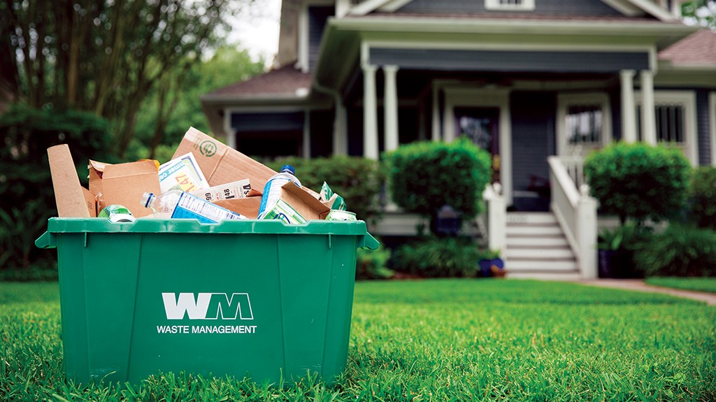 WM recycling bin full at the curb in front of a house