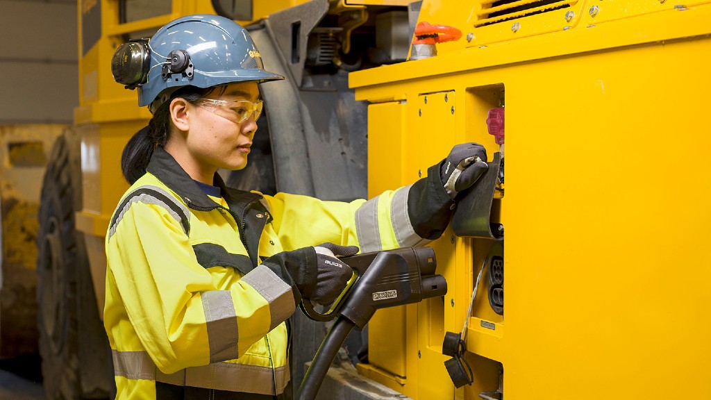 A worker is plugging in a charging cable into a piece of electric equipment