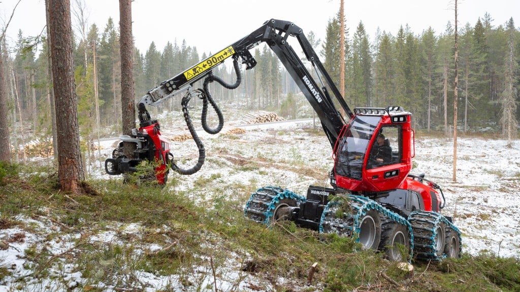 A wheeled forestry harvester cutting down a tree