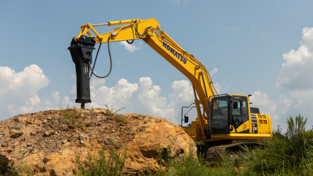 A hydraulic breaker attached to an excavator breaks ground on a job site