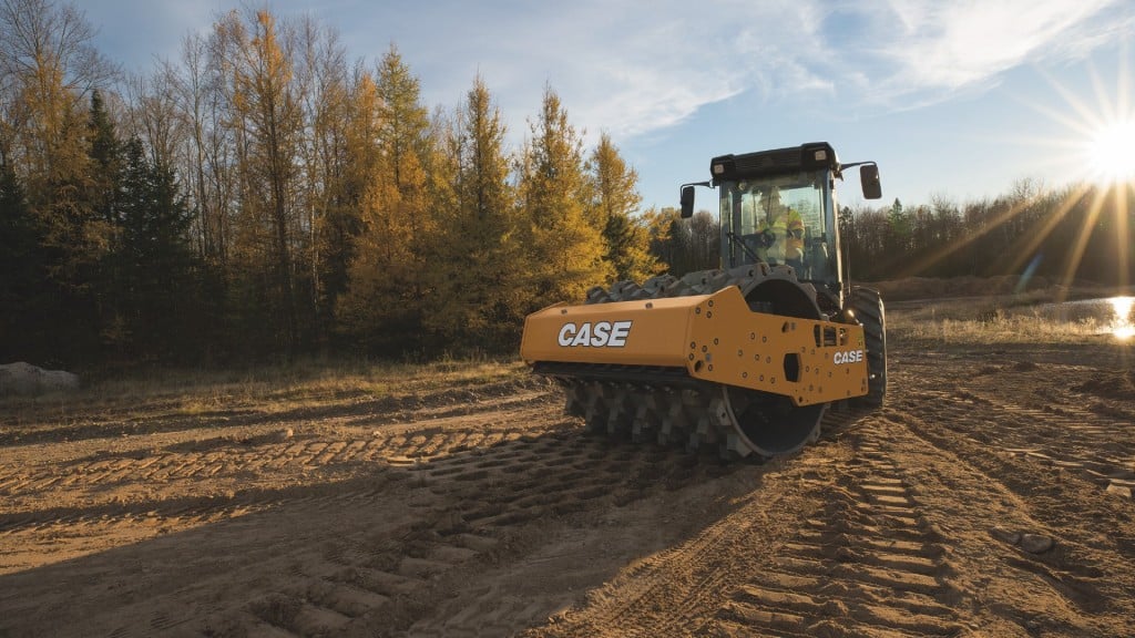 An operator compacts soil using a vibratory roller on a job site