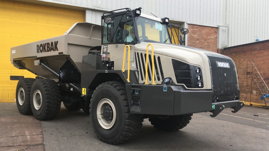 An articulated hauler parked in front of a garage