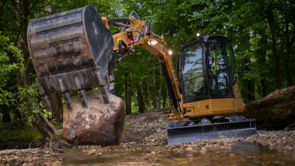 A Cat mini excavator moving a large rock