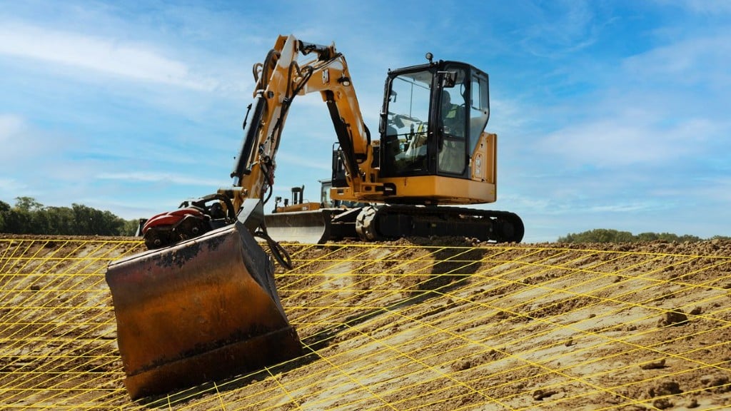 An excavator digs on the job site using grading technology