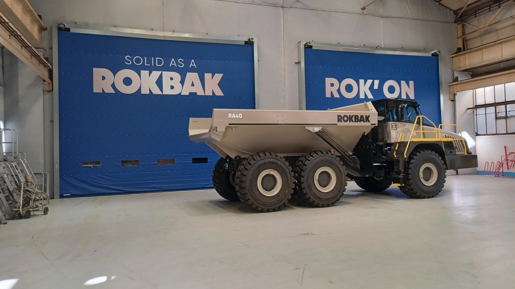 An articulated hauler parked in front of two garage doors